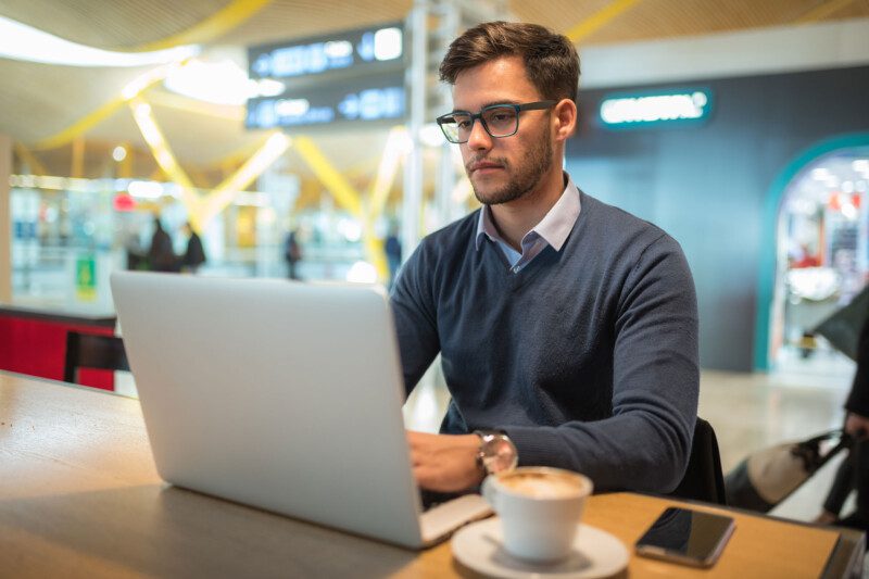 Person with laptop and coffee travel manager